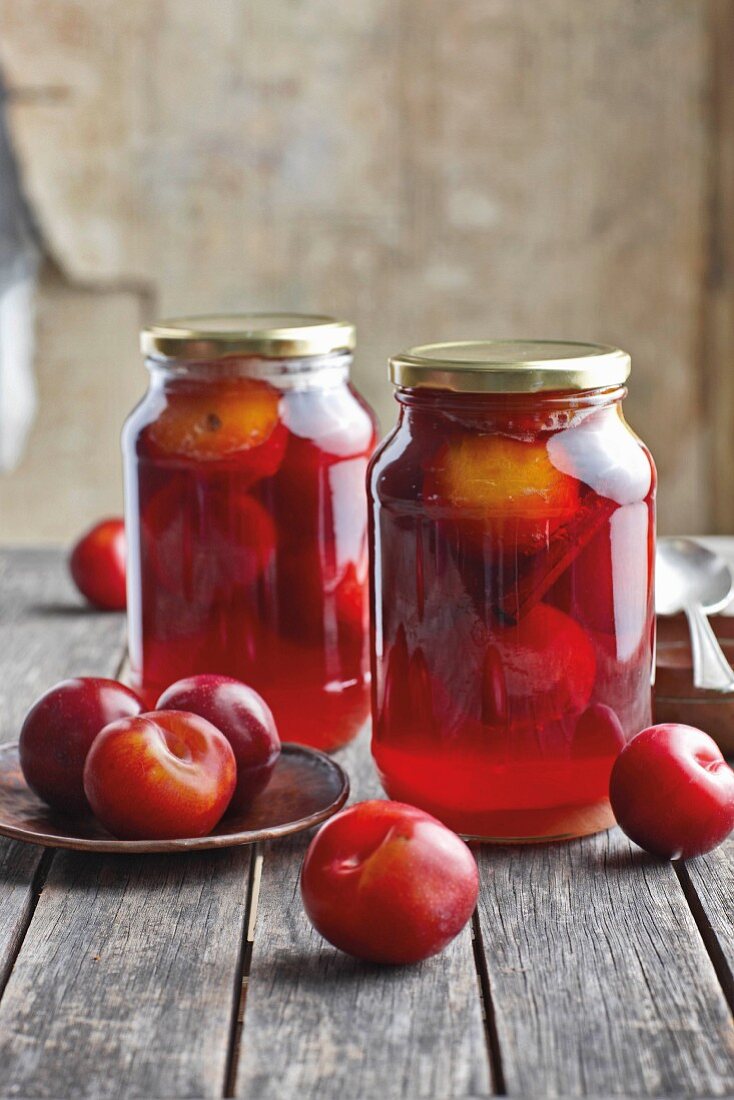 Jars of preserved red plums with cinnamon and honey