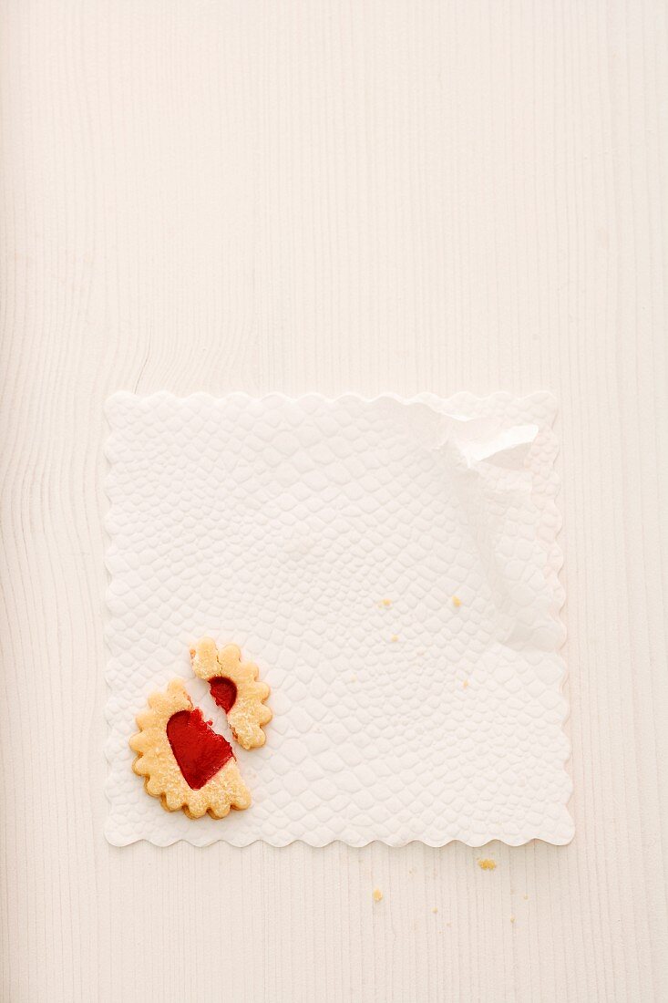 A broken jam biscuit on a doily (seen from above)