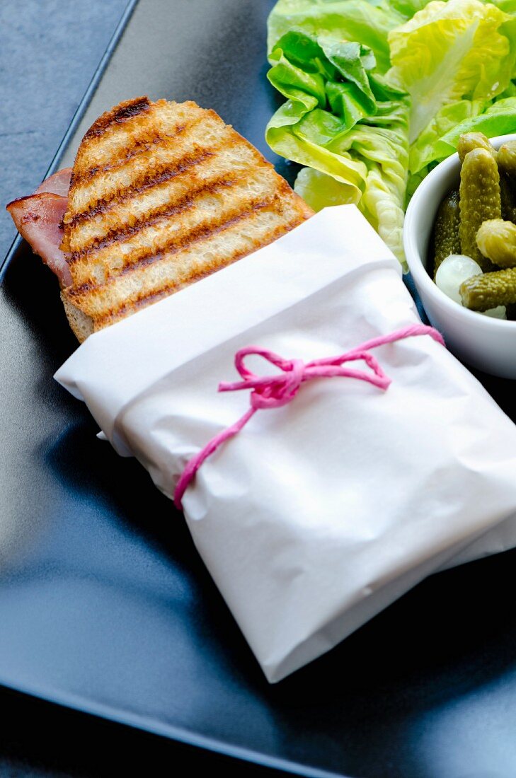 A ham and cheese panini wrapped in paper