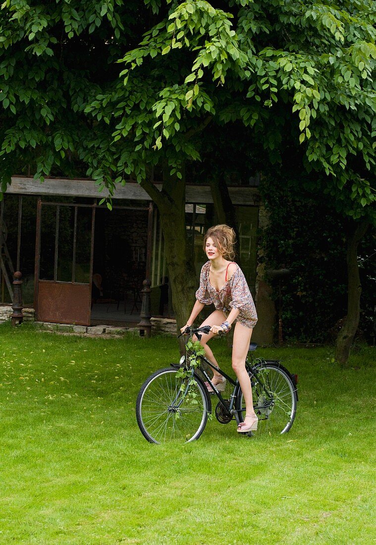 A woman wearing underwear and a floral-patterned blouse riding a bike