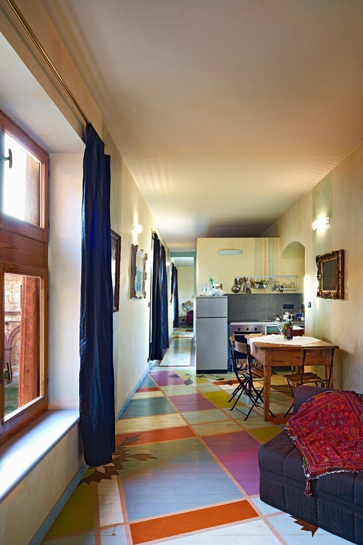 Moderne Küchenzeile und Essplatz in langestrecktem, offenem Raum mit grafisch gestaltetem Fussboden