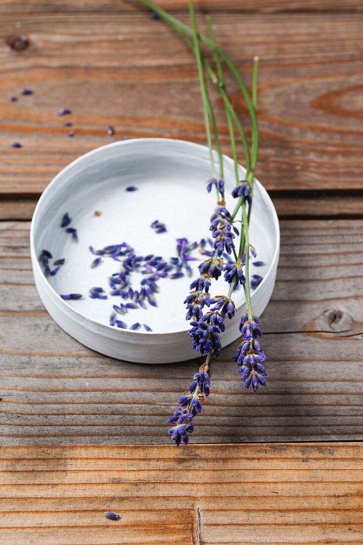 Lavender flowers in a bowl on a wooden surface