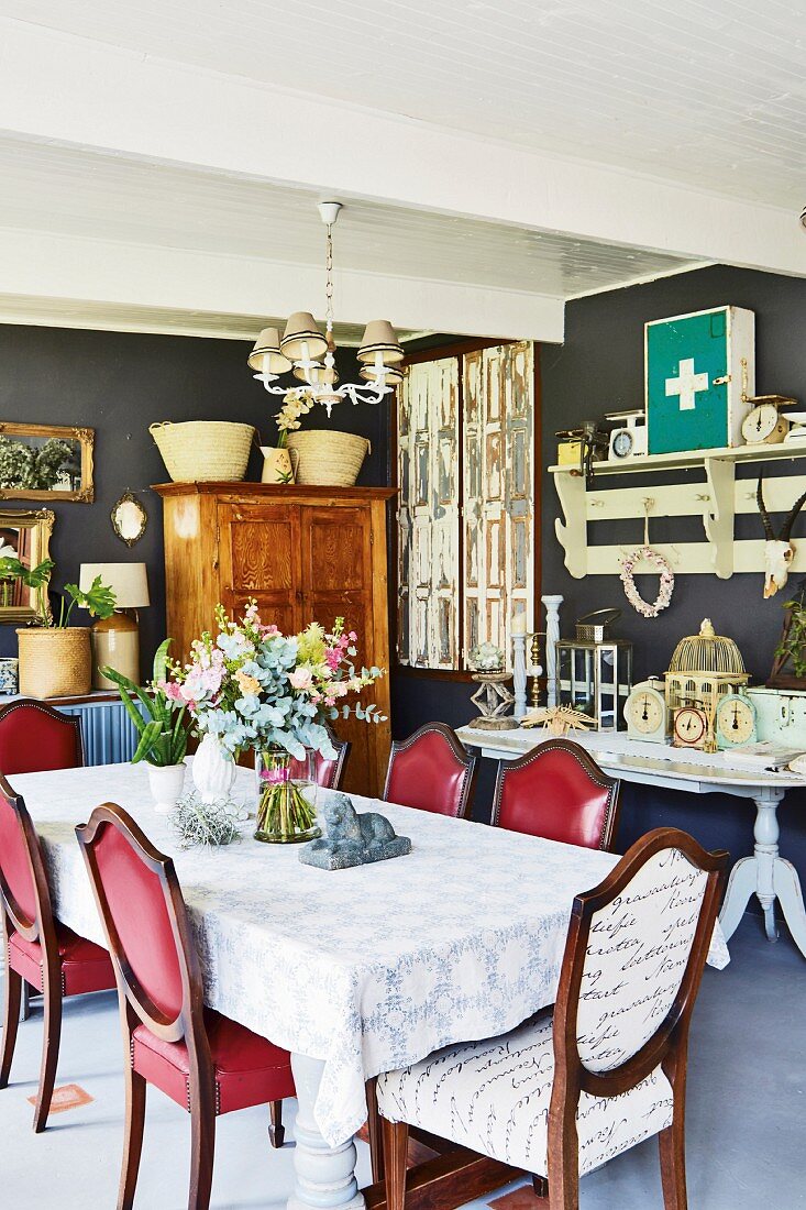 Antique chairs with red upholstery, shelves with hooks above console table and cabinet in background in vintage dining room