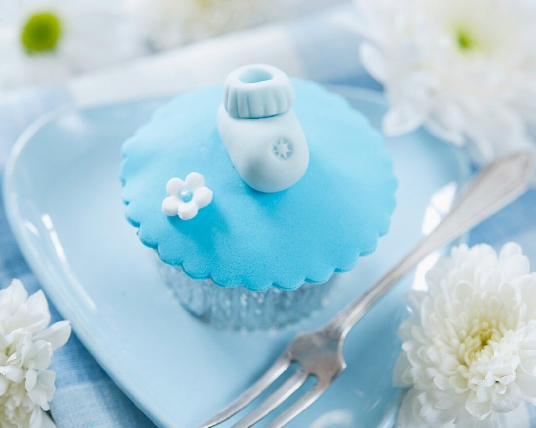 A cupcake decorated with a baby shoe