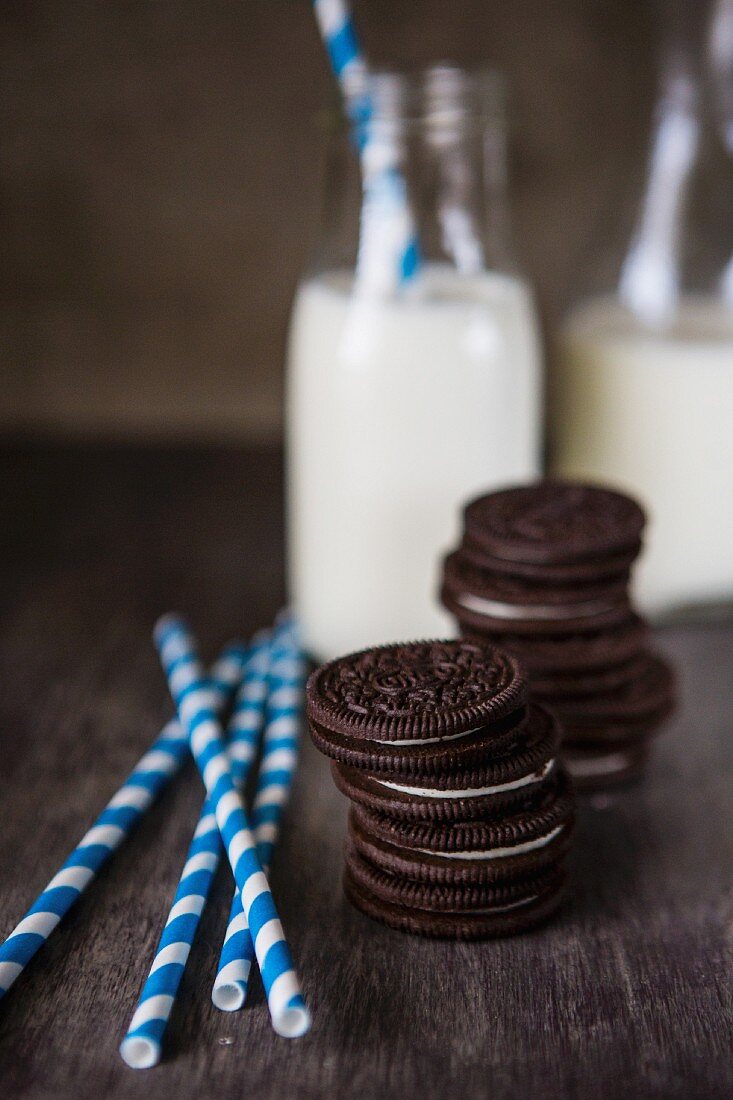 Two stacks of Oreo cookies with striped straws and two bottles of milk