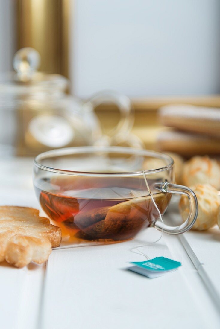 Peppermint tea in a glass cup served with biscuits and pralines