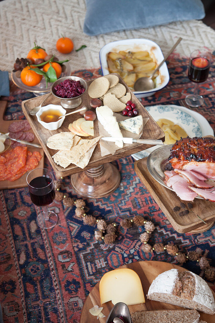 Weihnachtsmenü im Picknickstil auf Kelim mit Käseplatte und Schinkenbraten