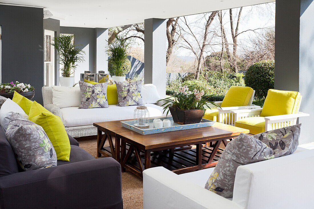 Covered terrace with seating area and colourful cushions with yellow accents