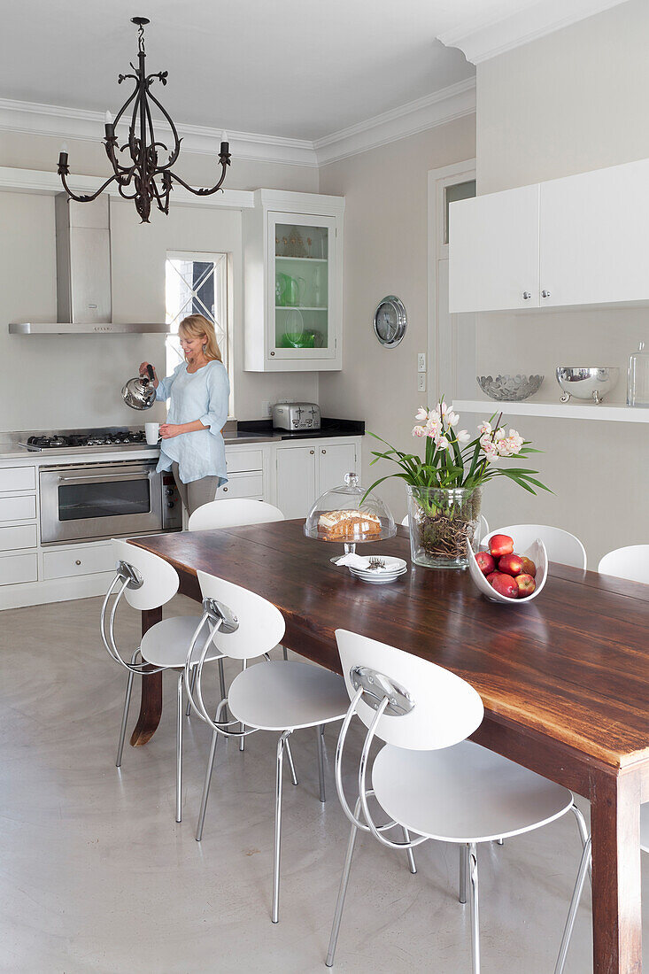 Woman in brightly decorated kitchen with wooden dining table and modern chairs