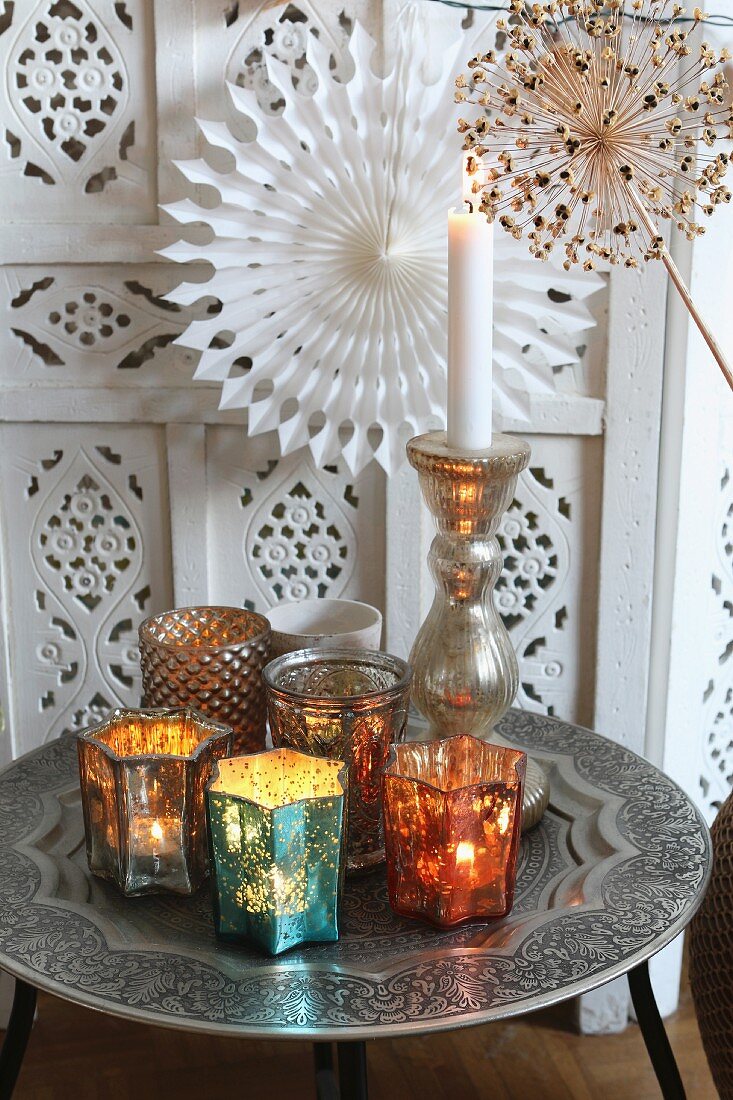 Orientalischer Tabletttisch mit farbigen Windlichtern und brennender Kerze