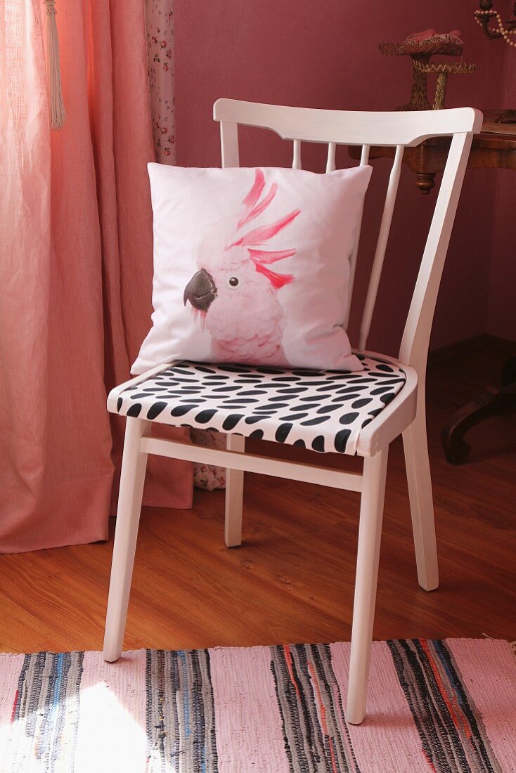 Upcycling: pink-painted kitchen chair with black and white seat cushion and scatter cushion with cockatoo motif