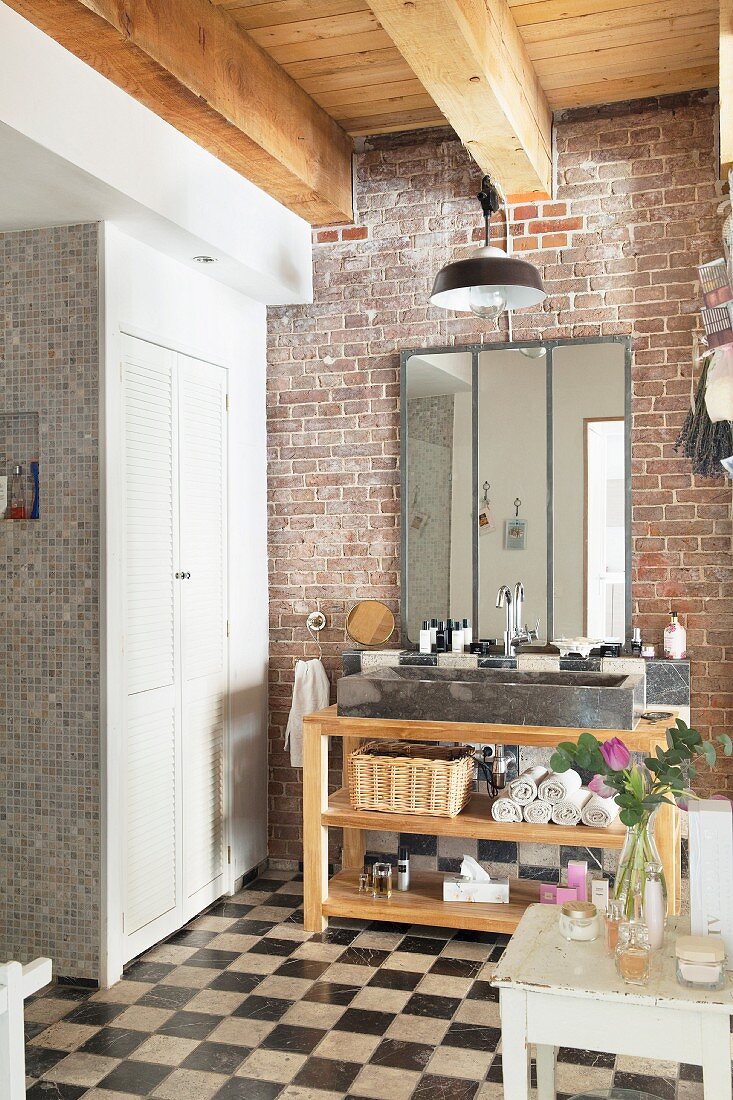 Bathroom with chequered floor, brick wall and washstand with trough-style sink on wooden frame