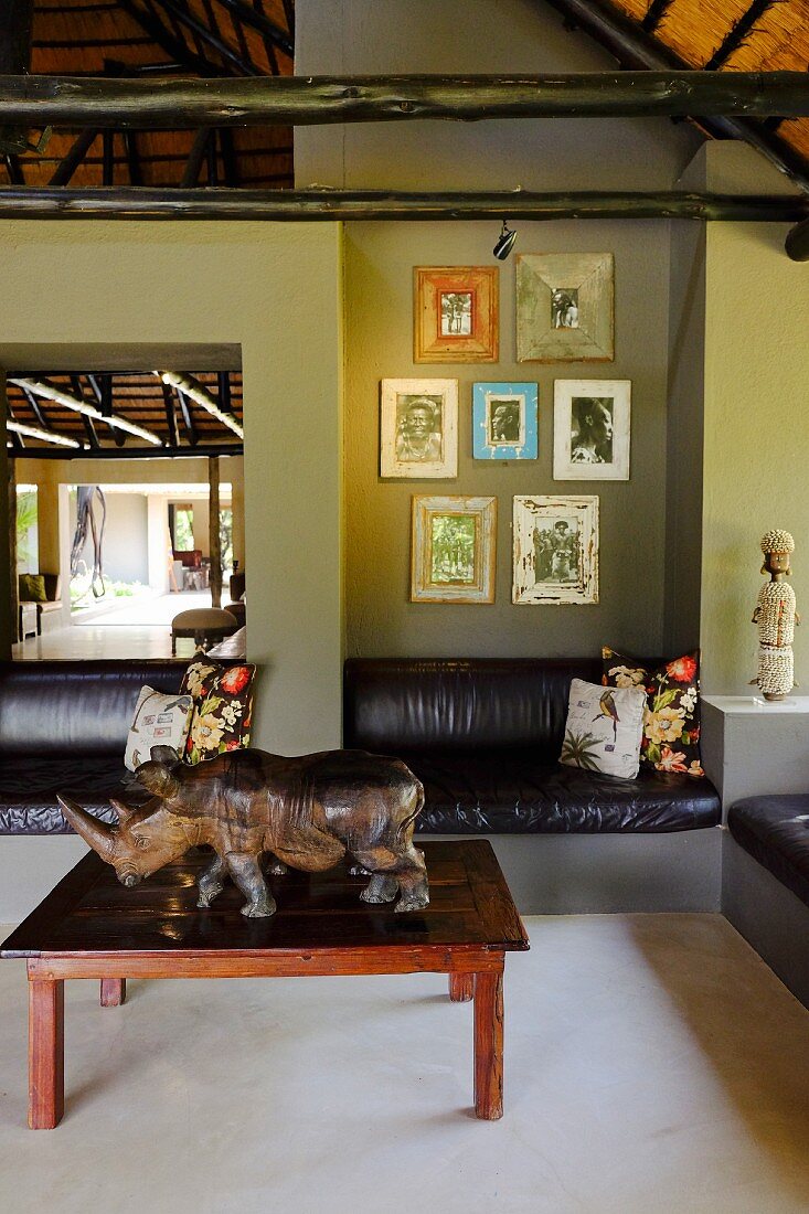 Grün getönter Loungebereich, an Wand eingebaute Ledersitzbänke, davor Couchtisch mit Nashornfigur