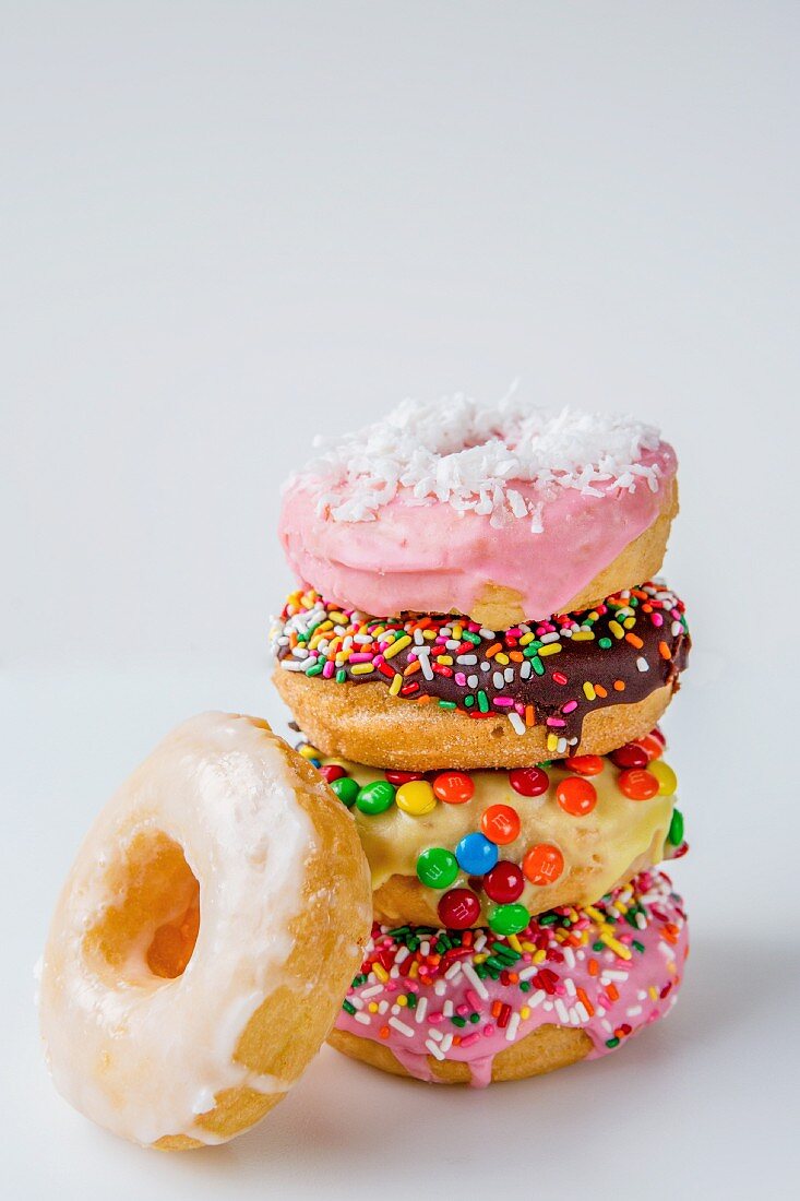 A stack of colourfully decorated doughnuts on a white surface