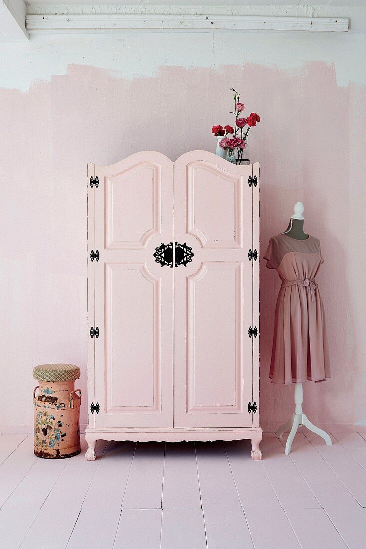 Pink-painted farmhouse wardrobe with black wrought iron fittings in pink interior