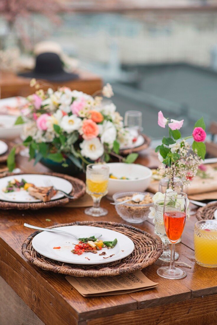 Leergegessene Teller auf festlich gedecktem Tisch mit grossem Blumengesteck
