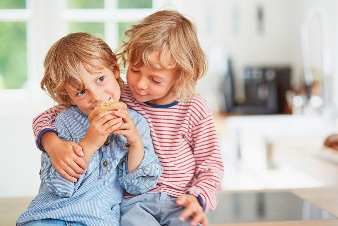 Kleine Jungen mit Muffin auf einer Küchentheke sitzend