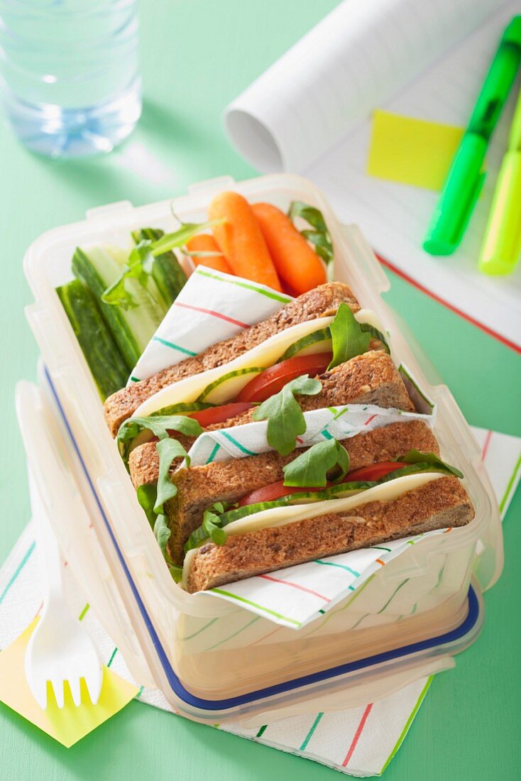 A cheese sandwich and raw vegetables in a lunch box