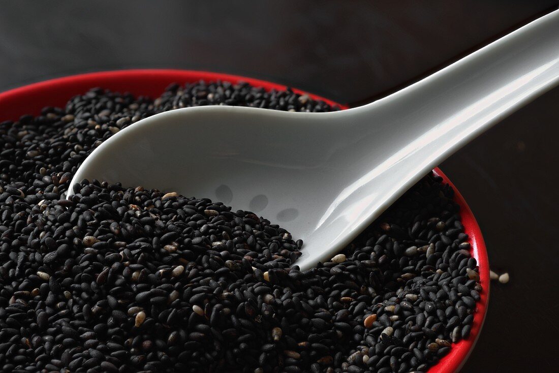 Roasted black sesame seeds with a porcelain spoon in a bowl
