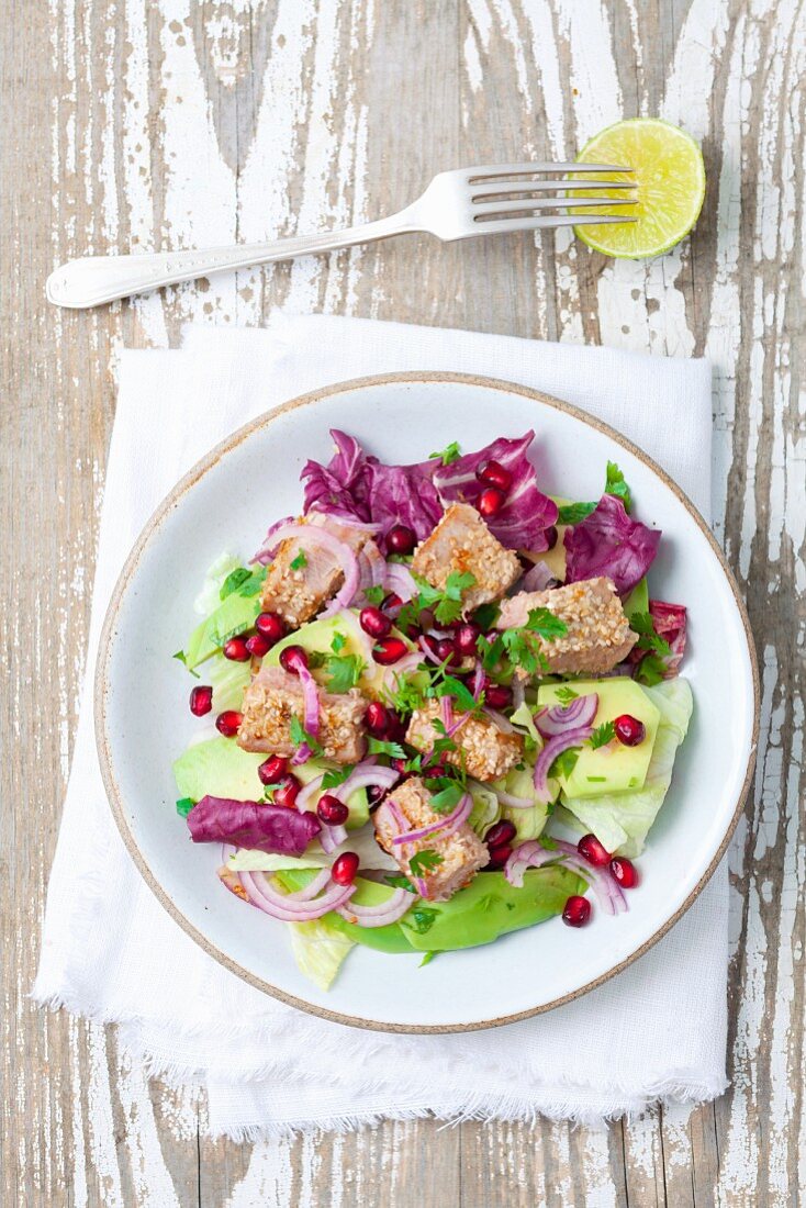 Salad with avocado, sesame seed tuna, red onions and pomegranate seeds