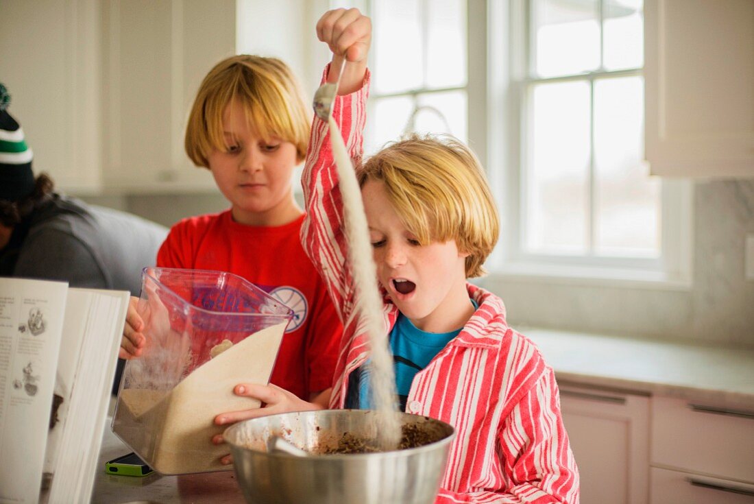 Brothers pouring flour into mixing bowl in a kitchen