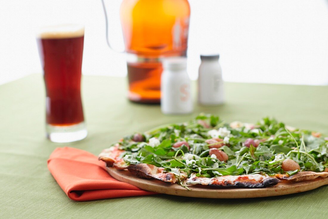 Pizza with rocket and cheese served with beer and salt and pepper