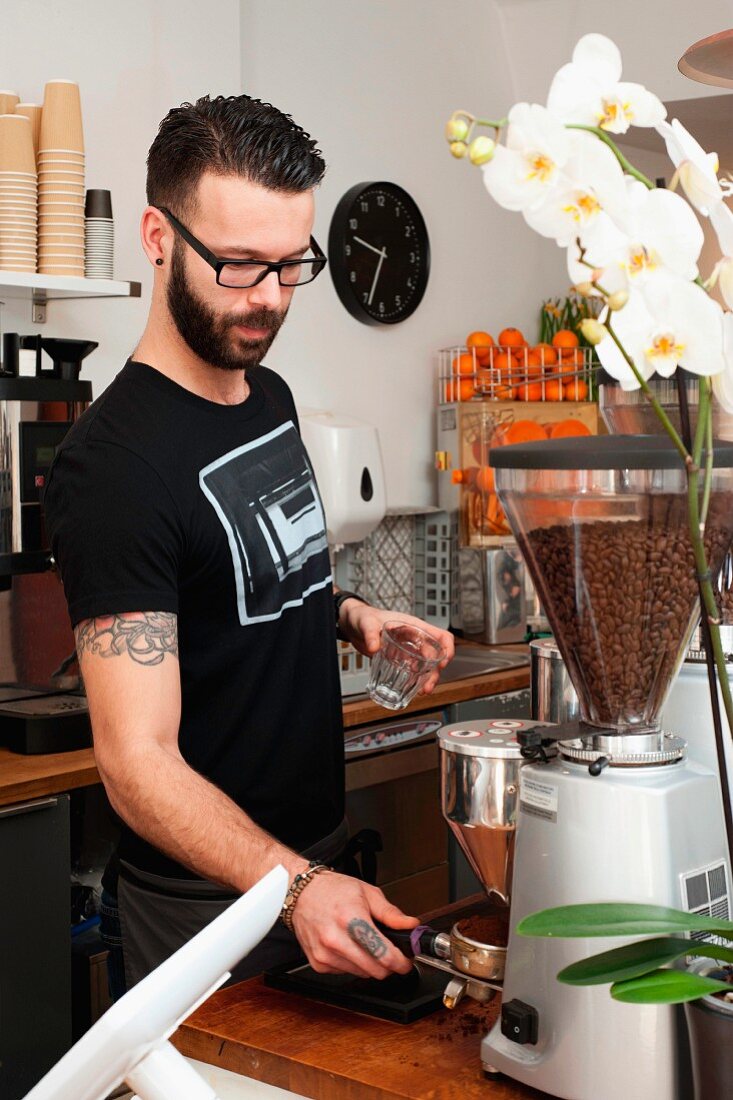 A young man making coffee in a cafe