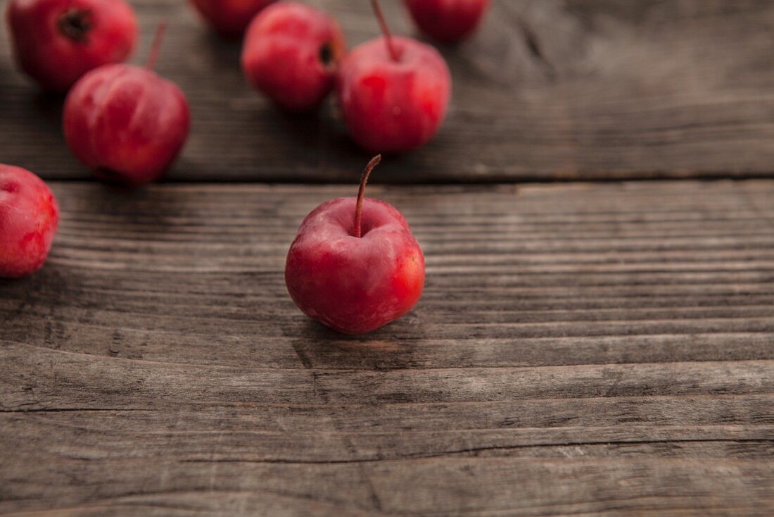 Red wild apples on a wooden surface