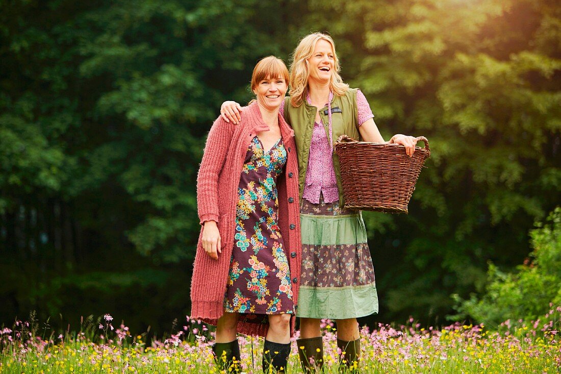 Two women standing in a meadow with a wicker basket