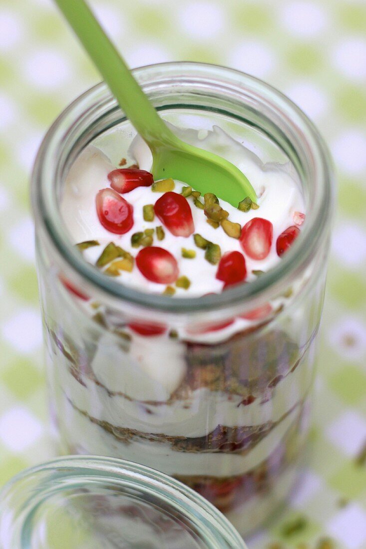 A layered desert with creamy yoghurt, biscuit crumbs, pistachios and pomegranate seeds