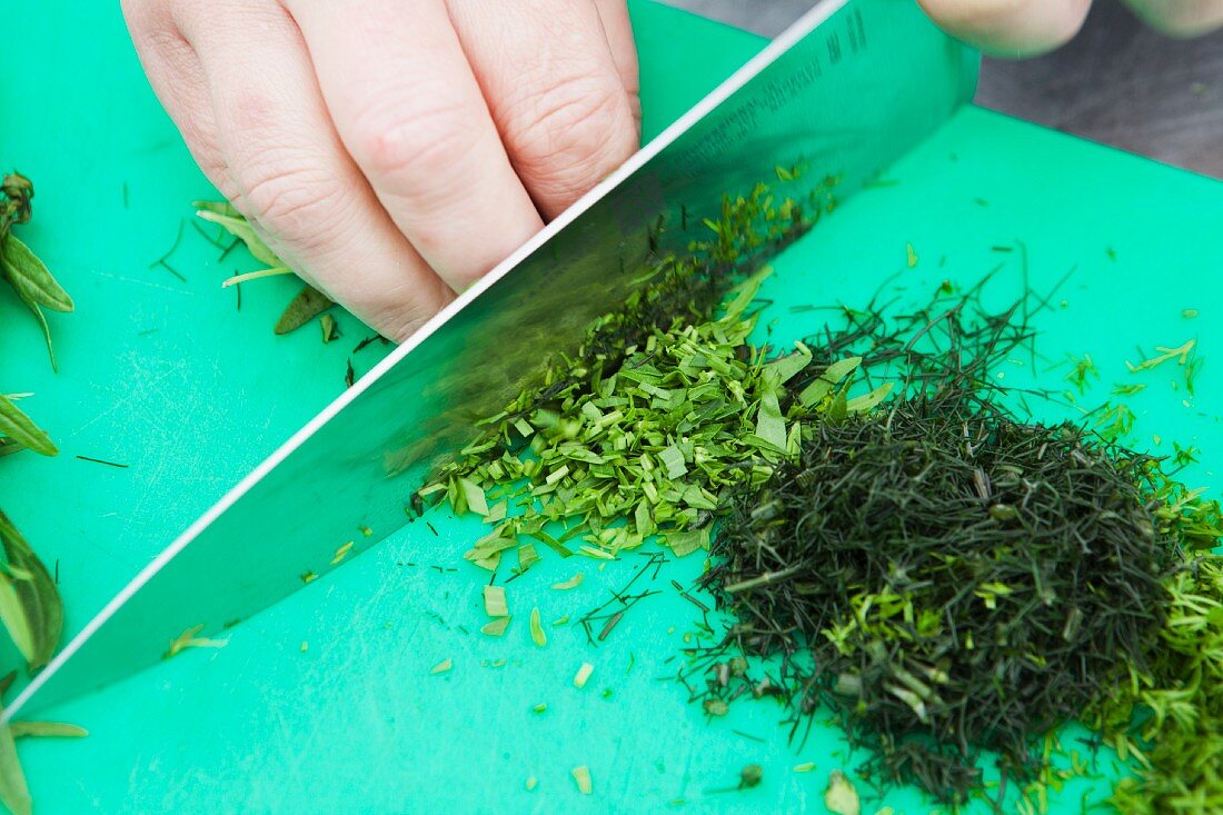 Herbs being chopped with a knife