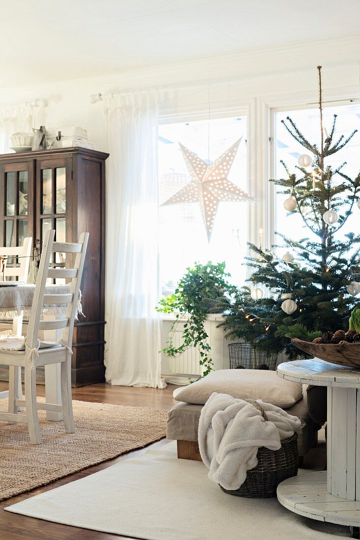 Simply decorated Christmas tree between cable-reel table and dining table