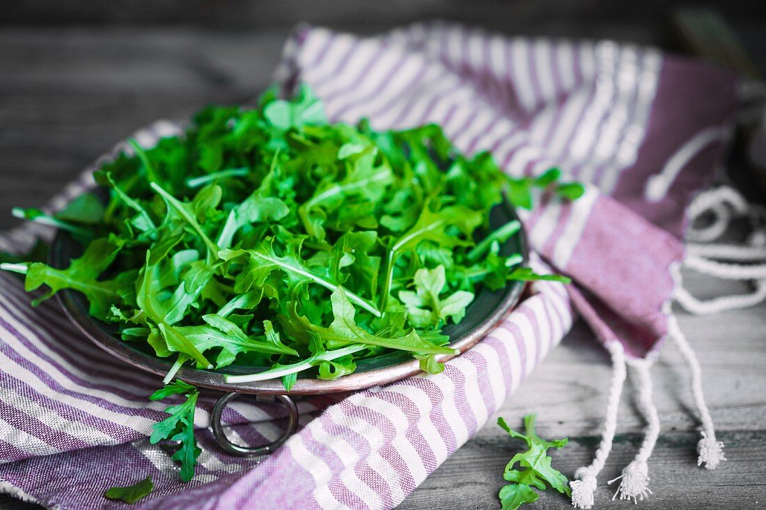 A bowl of rocket on a striped cloth