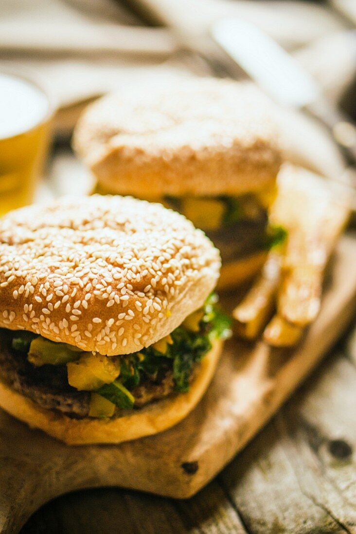 Gegrillter Cheeseburger mit Kartoffeln und Bier auf Schneidebrett