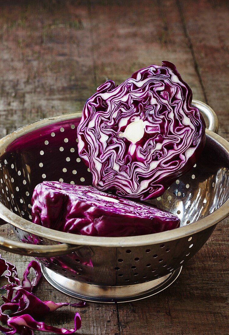 A halved red cabbage in a colander