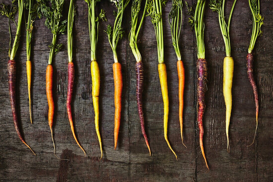 A row of colourful carrots on a wooden surface