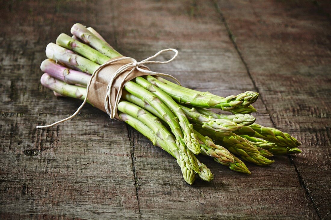 A bunch of green asparagus on a wooden board