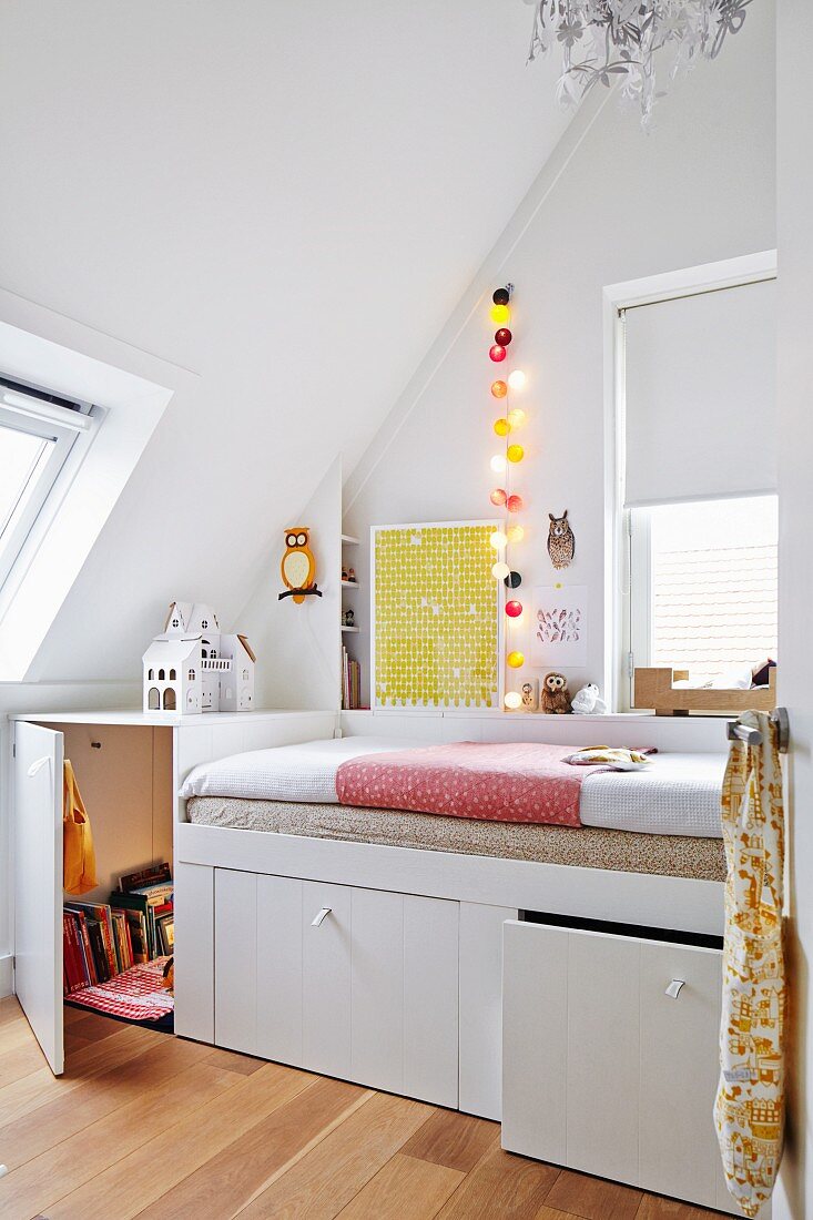 Custom-made white bed with storage drawers in teenager's bedroom with sloping ceiling