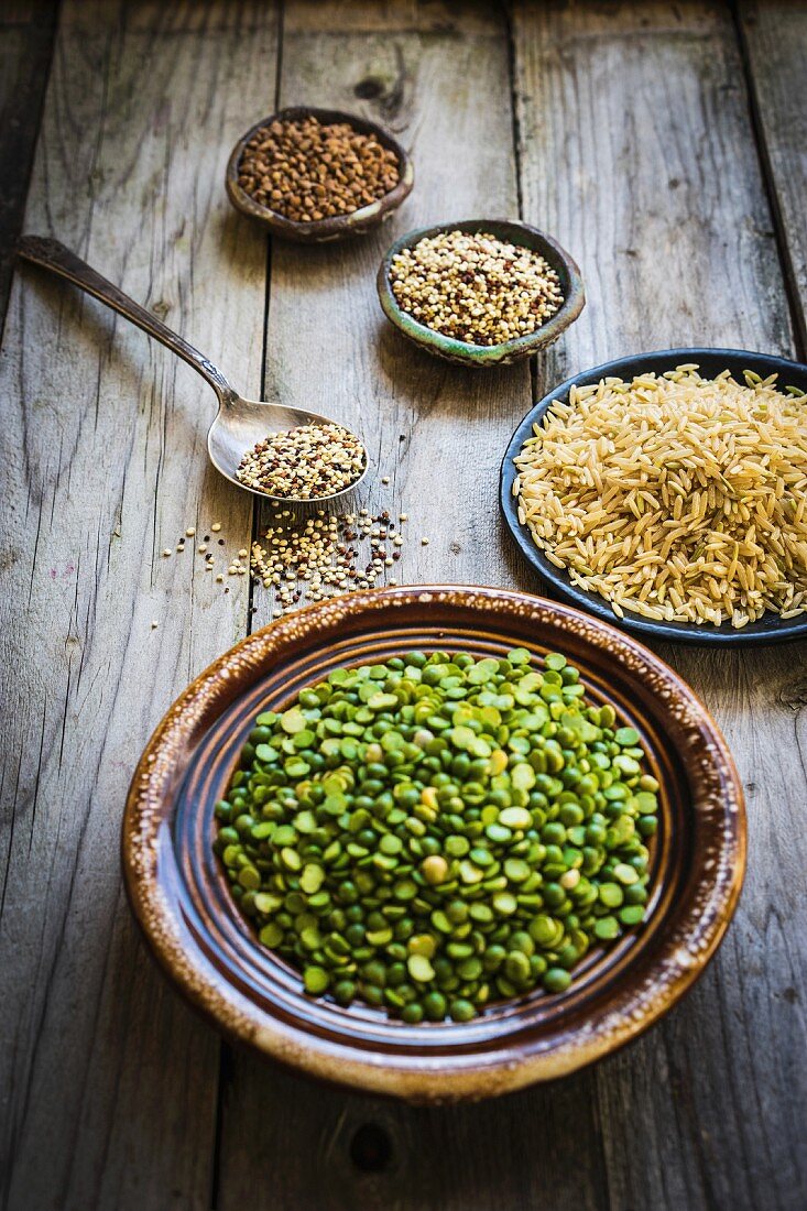 Split peas, brown rice, quinoa and buckwheat on a wooden surface