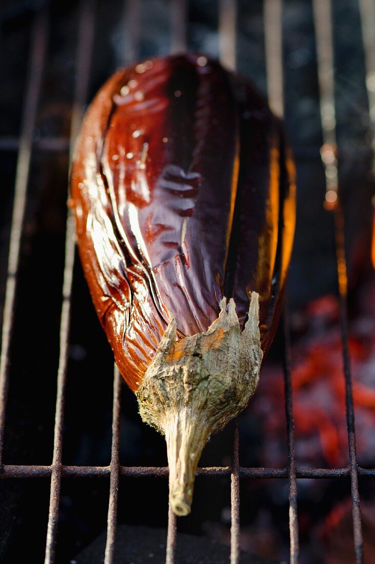 A whole aubergine on a barbecue