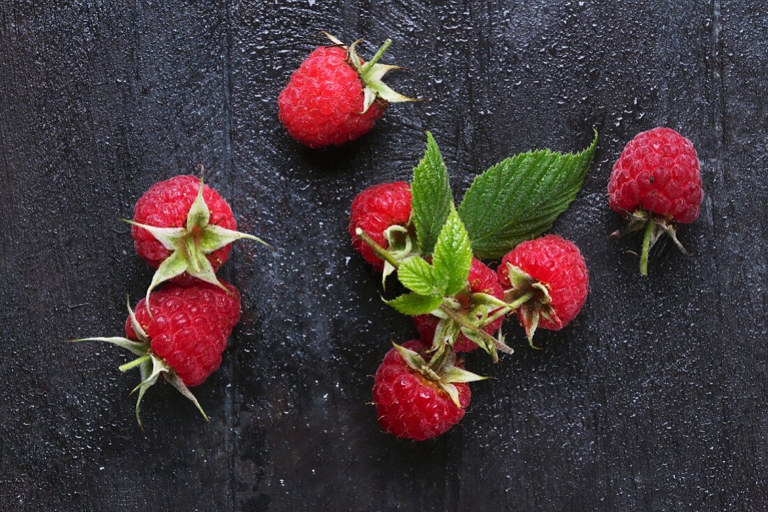 Raspberries with leaves on wooden surface