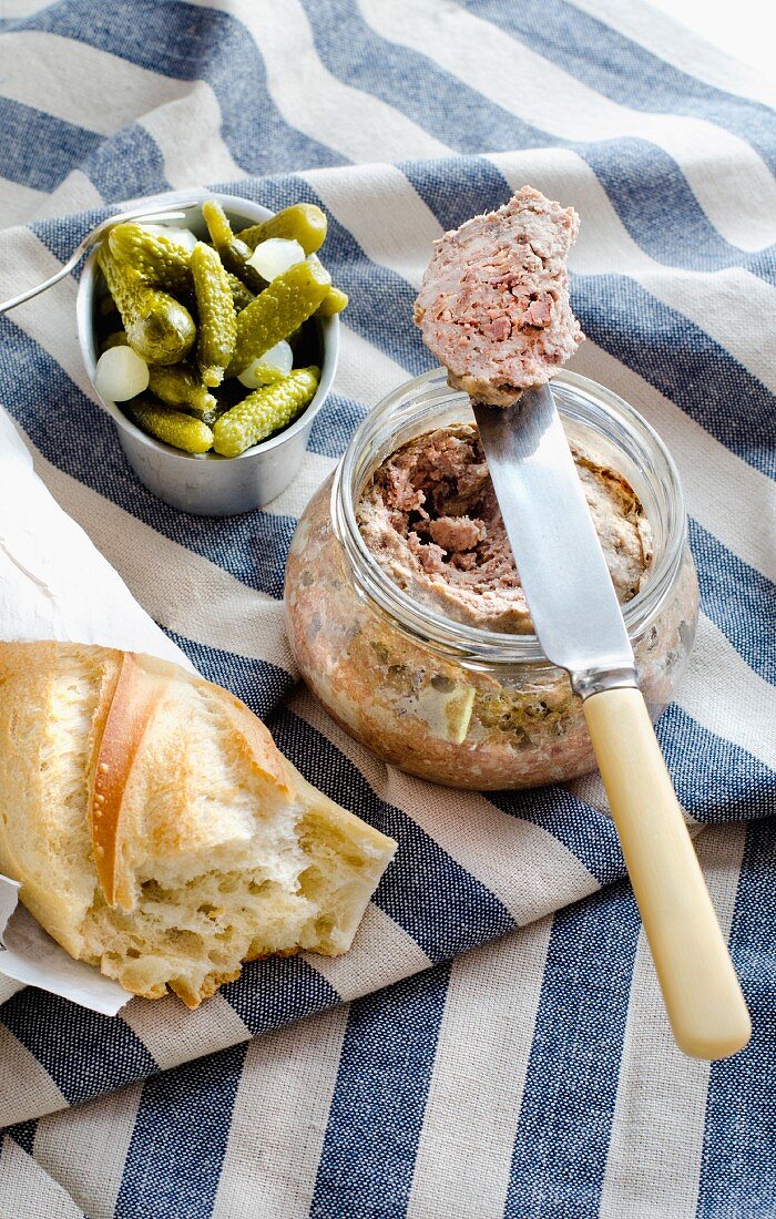 Ein Glas bretonische Pate de campagne mit Cornichons und Baguette