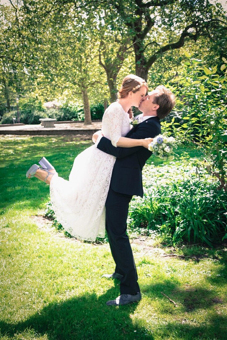 A young bride and groom kissing in a park