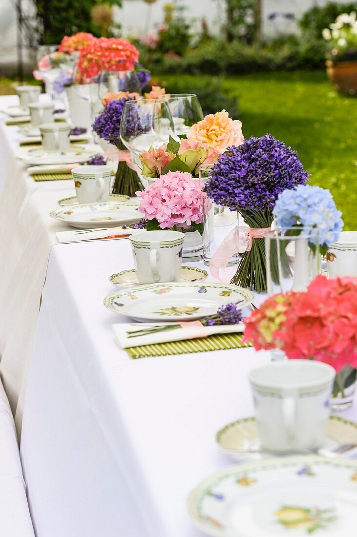 Long table set for afternoon coffee with posies of lavender and other flowers
