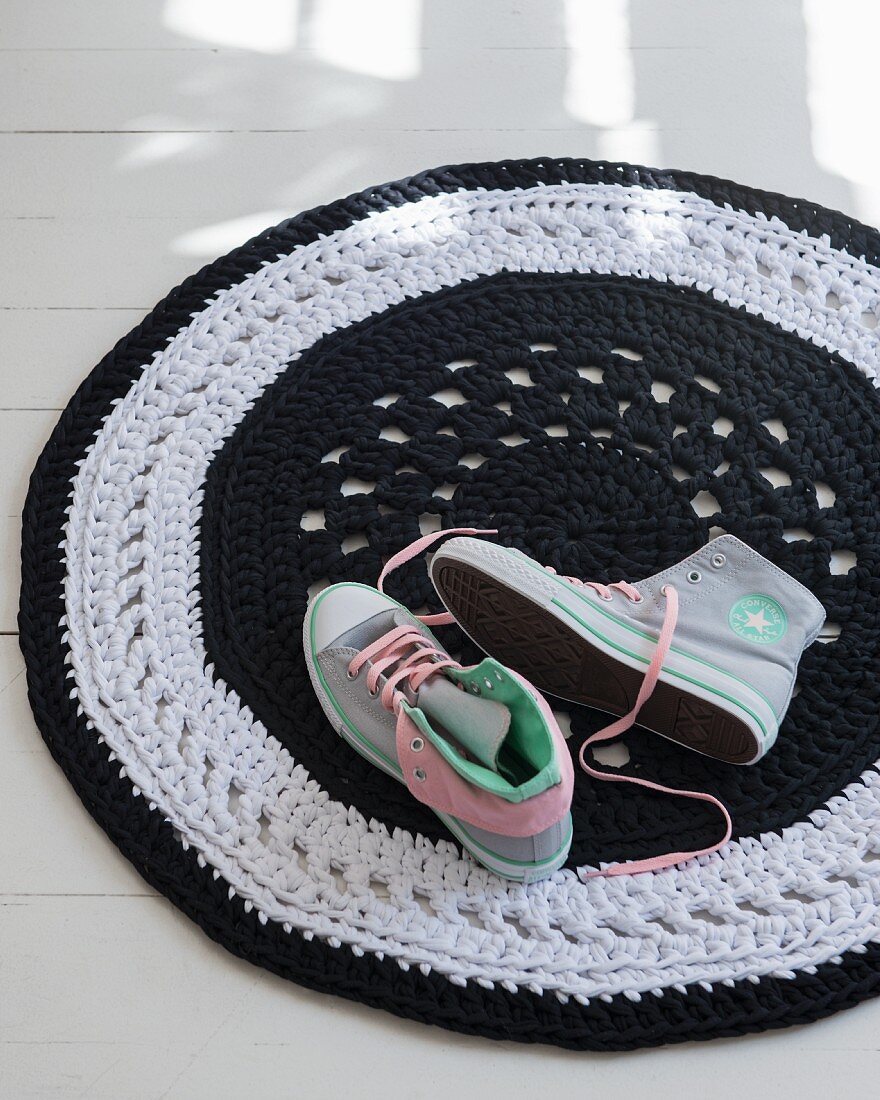 A round, crocheted rug and a pair of sneakers