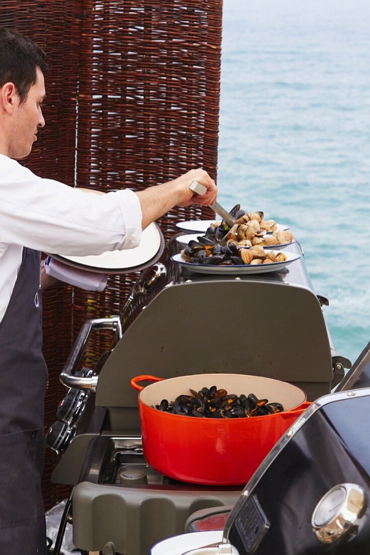 Koch serviert Muscheln bei einer Hochzeitsfeier am Meer