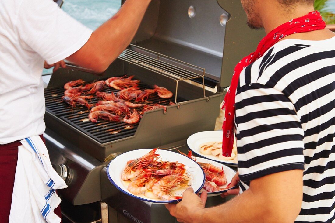 A waiter serving grilled prawns at a wedding by the sea