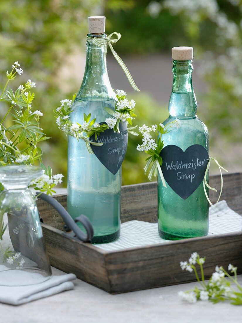 Bottles of homemade woodruff syrup as a gift decorated with hearts and wreaths