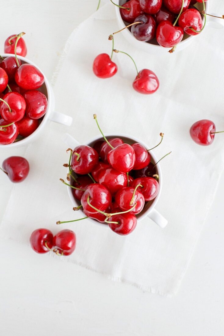 Fresh cherries in white cups (seen from above)