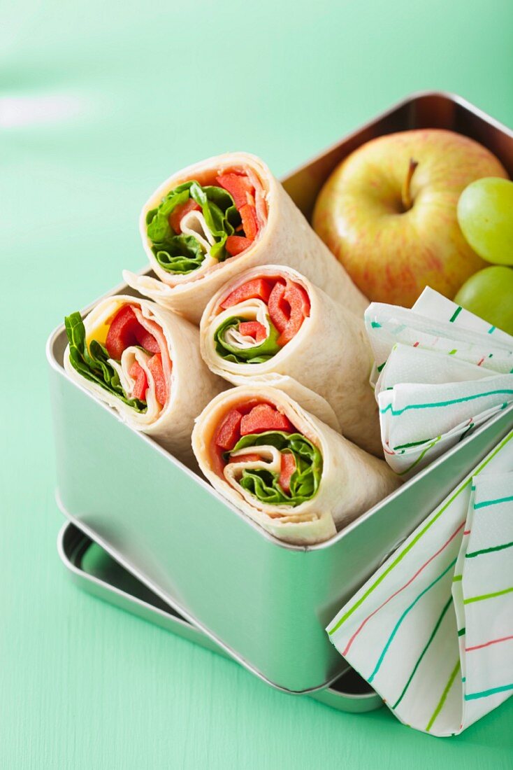 Schinken-Paprika-Wraps und Obst in einer Lunchbox